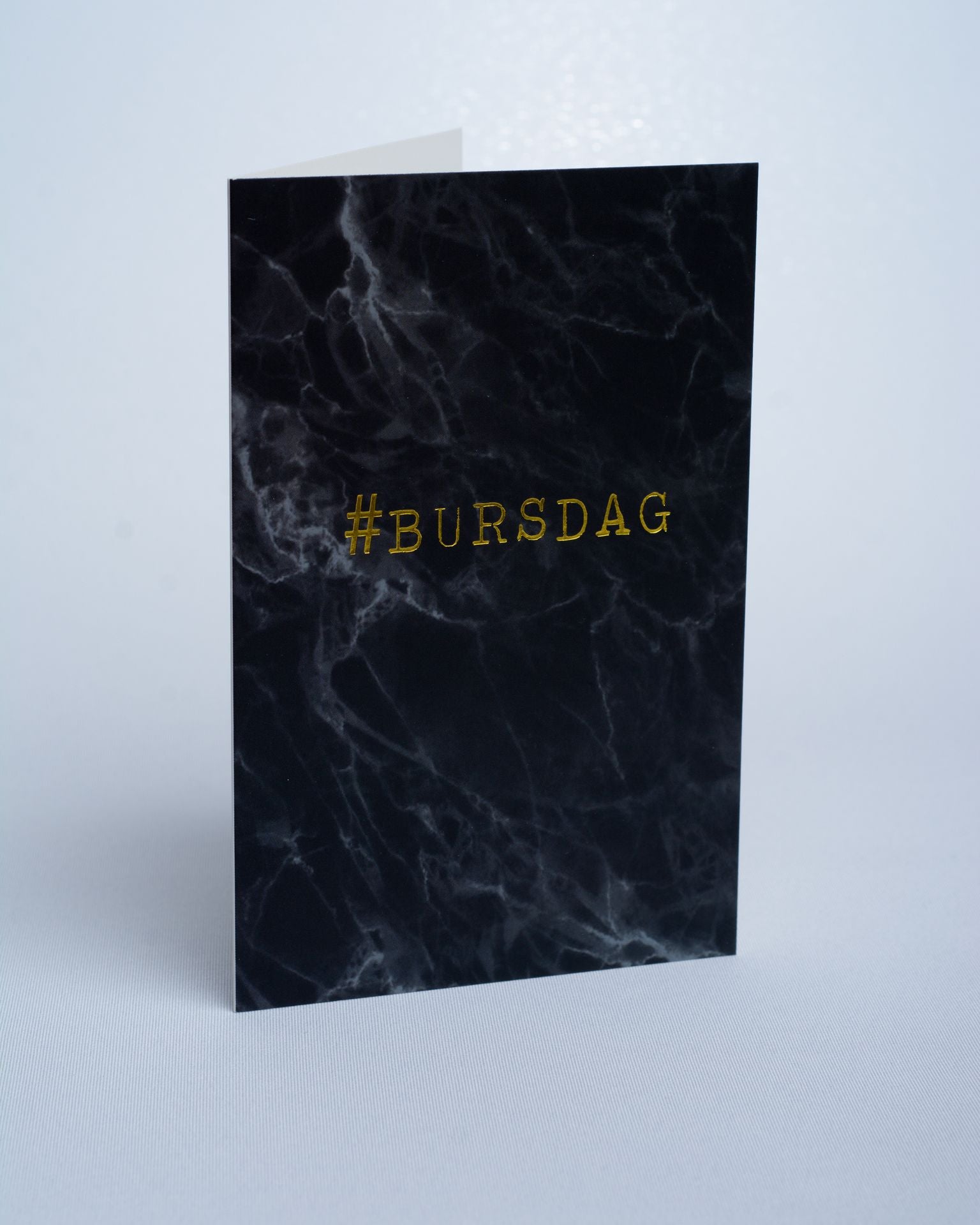 Dobbelt kort med sort marmortrykk og tekst i gull.   Størrelse på kortet er 10 cm x 15 cm.  Hvit konvolutt medfølger. Portfoliofoto.